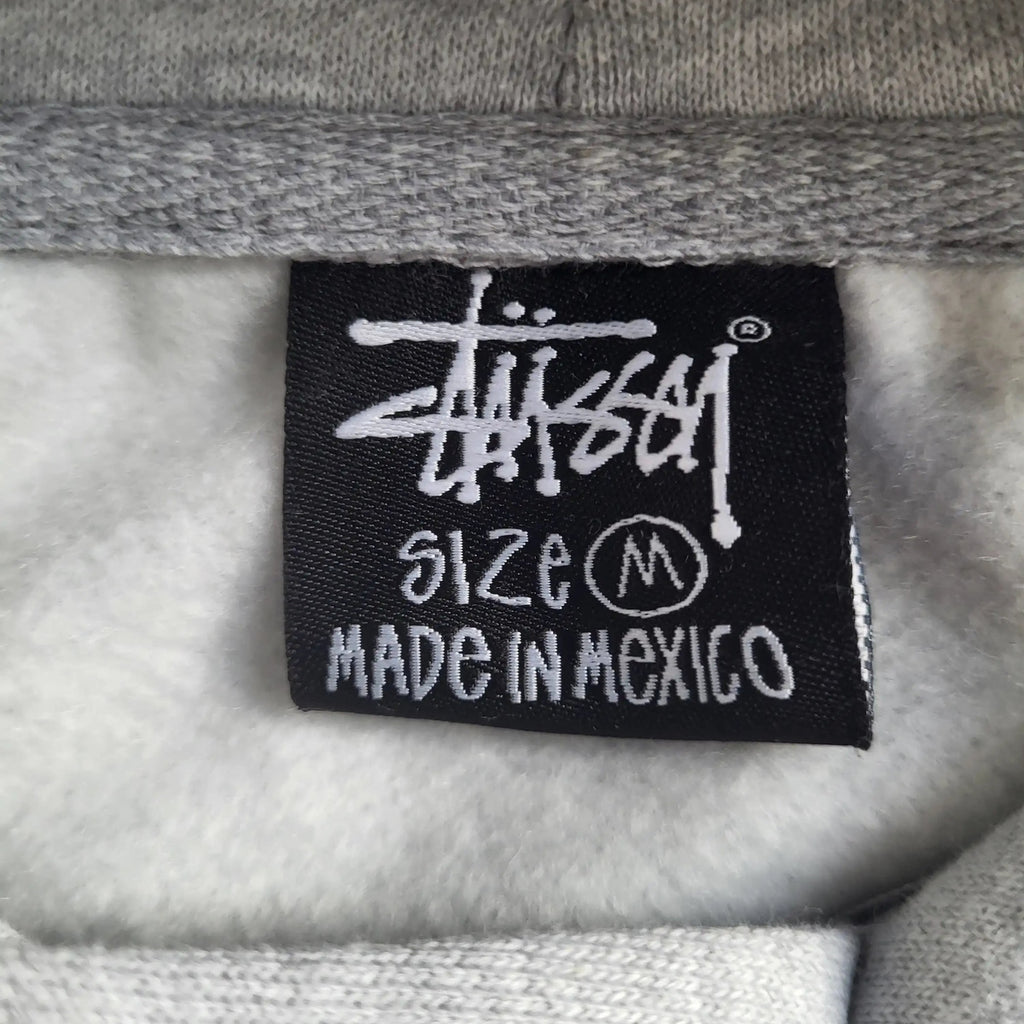 Sweat gris Stüssy taille M, étiquette visible. Fripes Sélect