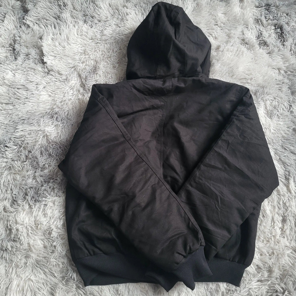 Veste noire à capuche Carhartt taille L, posée sur tapis gris. Fripes Sélect