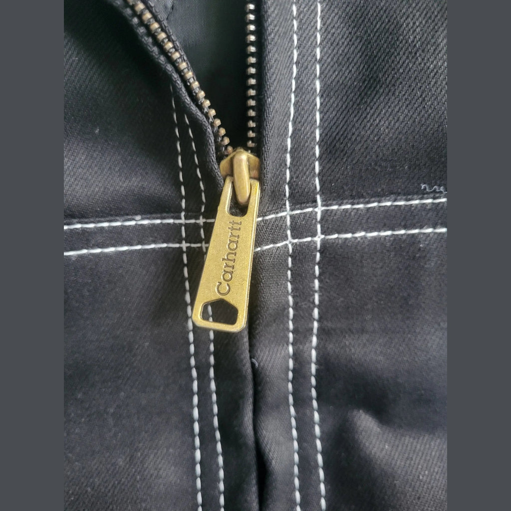 Veste Carhartt noire taille M avec surpiqûres blanches, détail fermeture éclair. Fripes Sélect