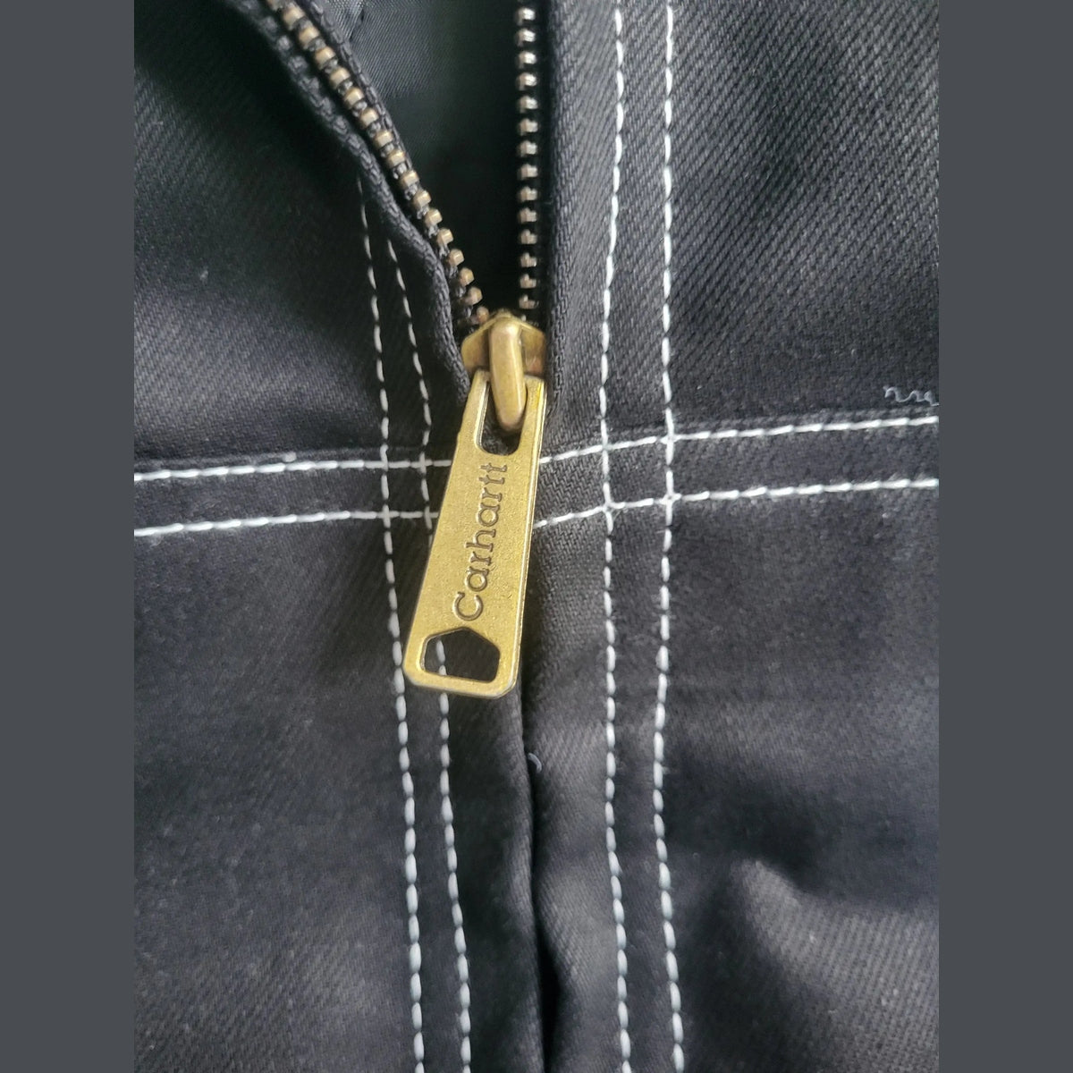 Veste Carhartt noire taille M avec surpiqûres blanches, détail fermeture éclair. Fripes Sélect