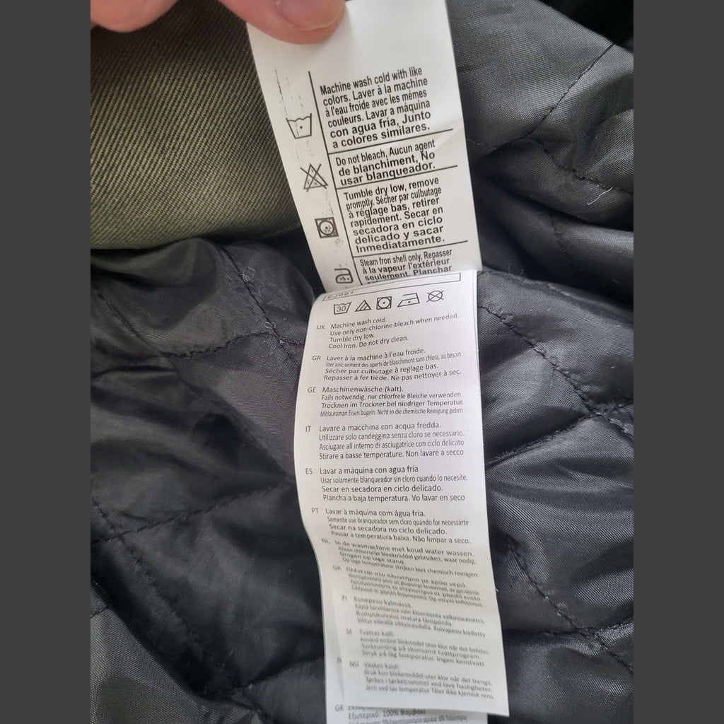 Étiquette d'entretien d'une veste kaki Carhartt, taille M. Fripes Sélect