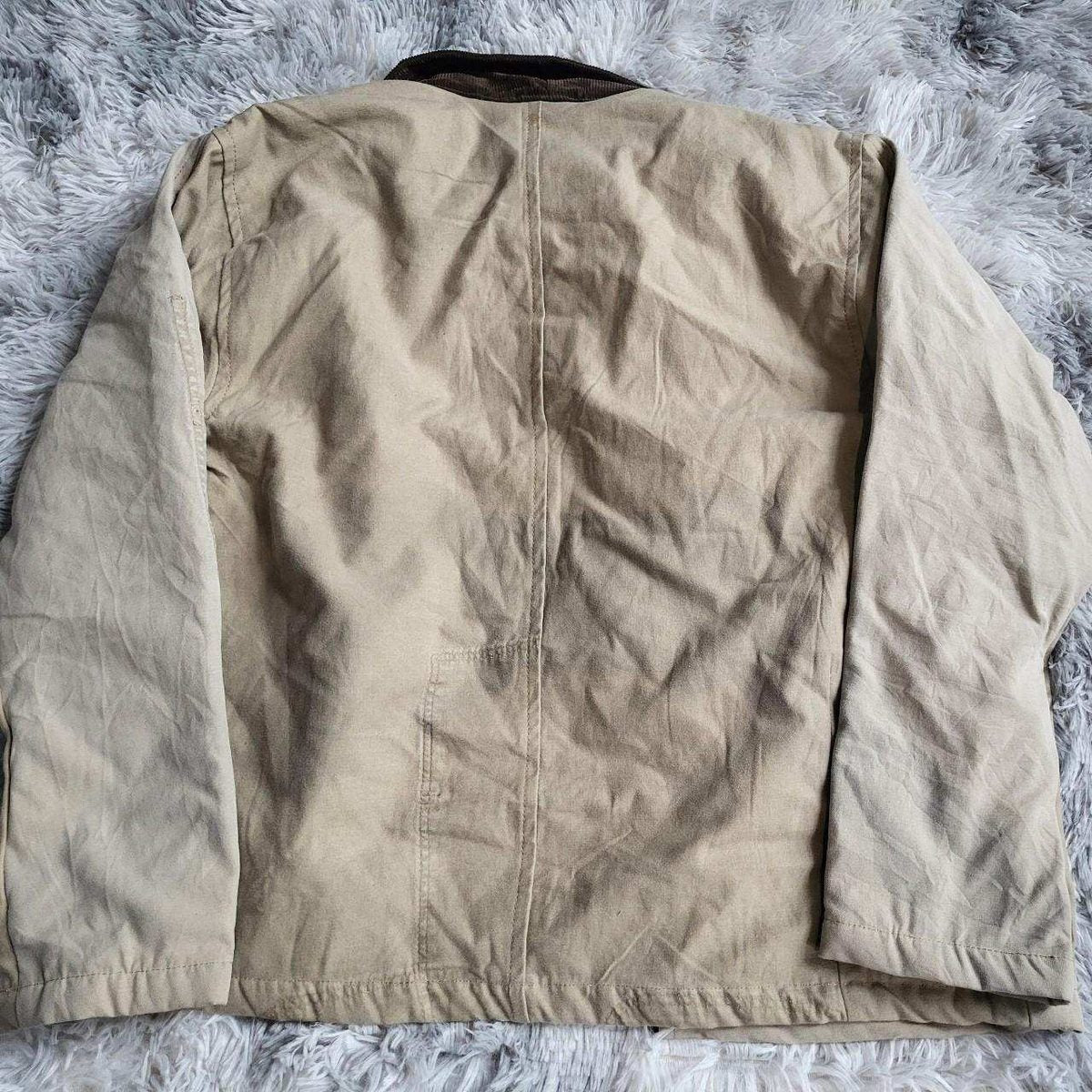 Veste Carhartt beige, taille non visible, posée sur fond en fourrure. Fripes Sélect