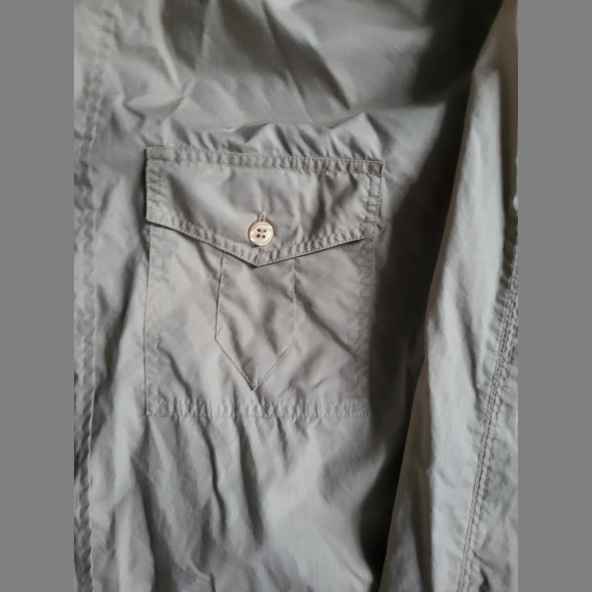 Chemise grise, poche poitrine, sans marque visible, taille non indiquée. Fripes Sélect