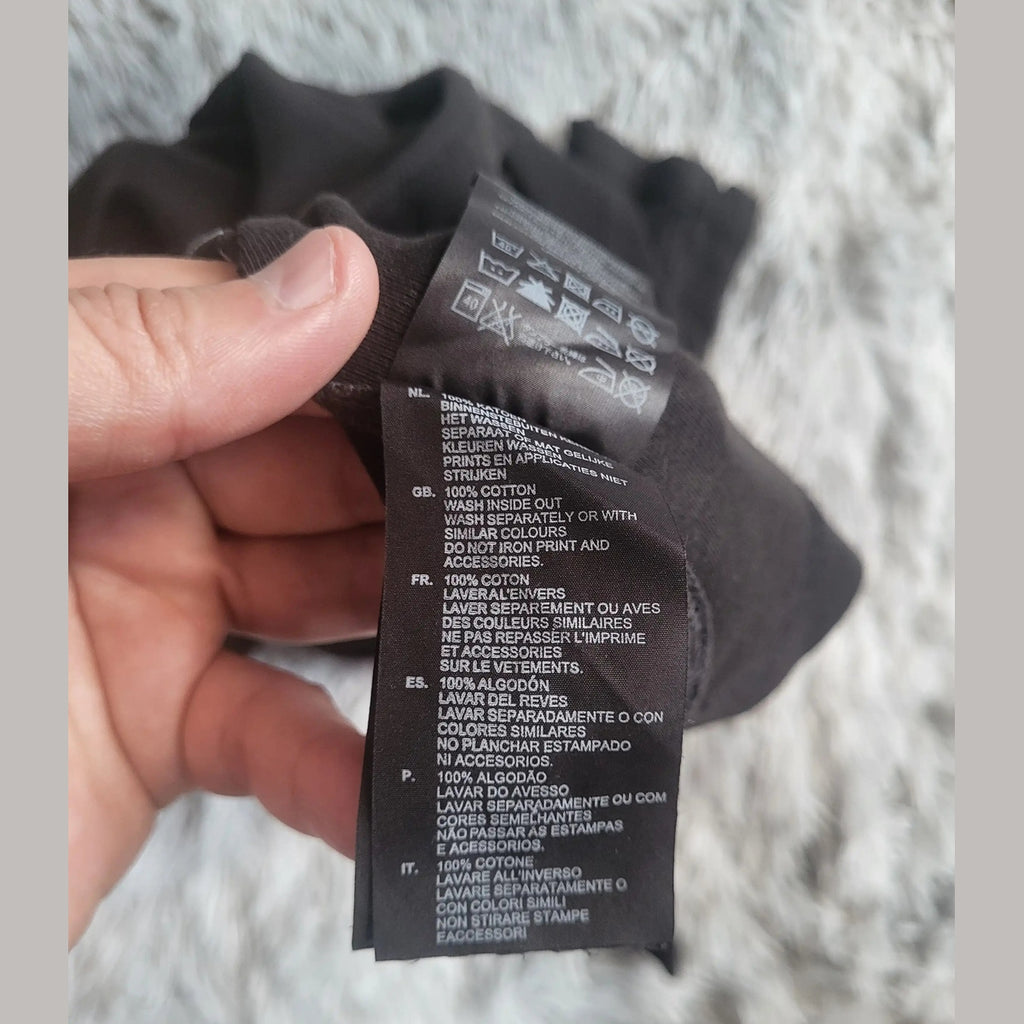 Étiquette d’un t-shirt noir 100% coton, taille non visible, sans marque apparente. Fripes Sélect