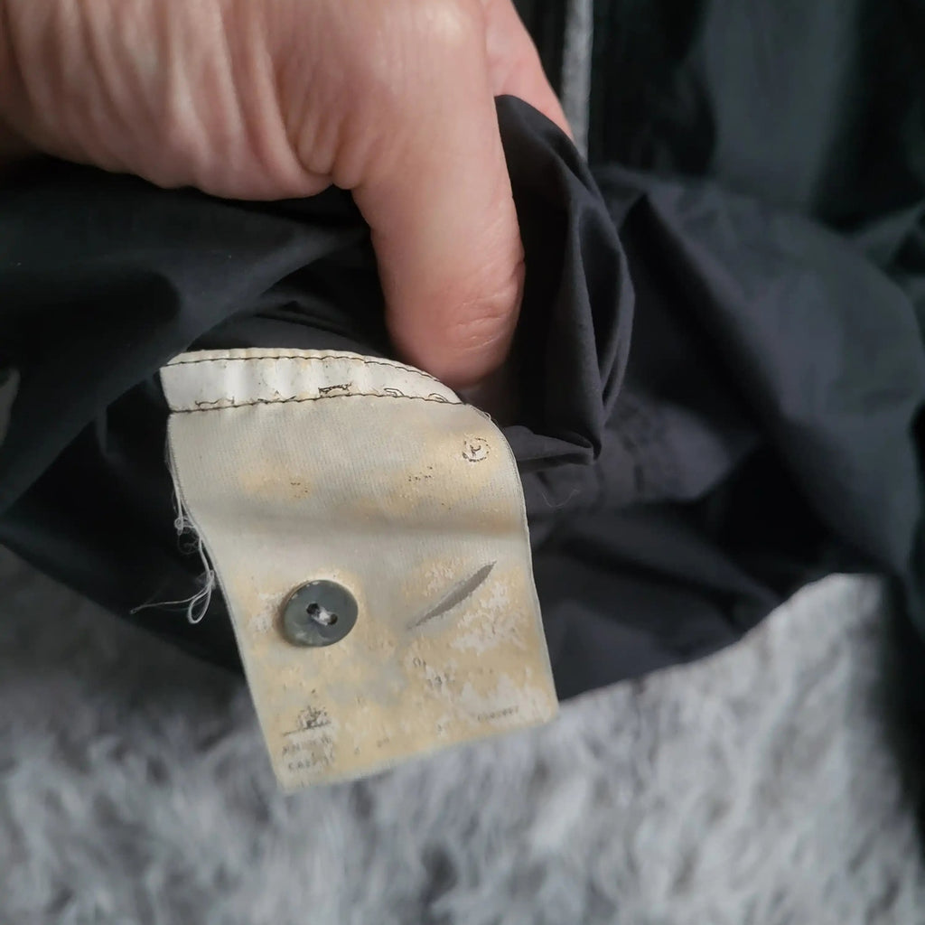 Veste noire, marque non visible, taille non lisible, tenue à la main. Fripes Sélect