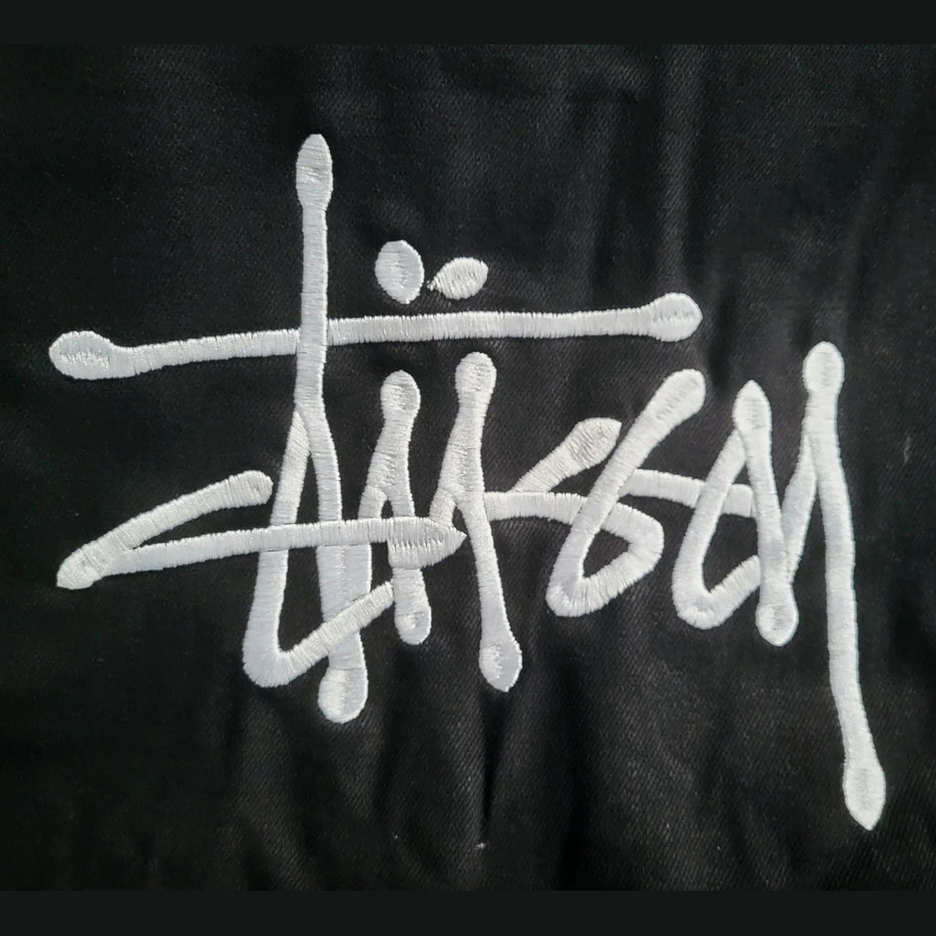 Veste noire Stüssy, logo brodé blanc, taille non indiquée. Fripes Sélect