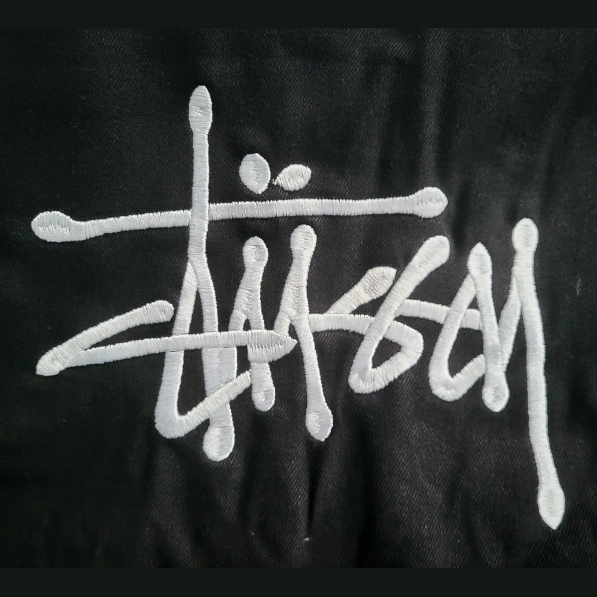 Veste noire Stüssy, logo brodé blanc, taille non indiquée. Fripes Sélect