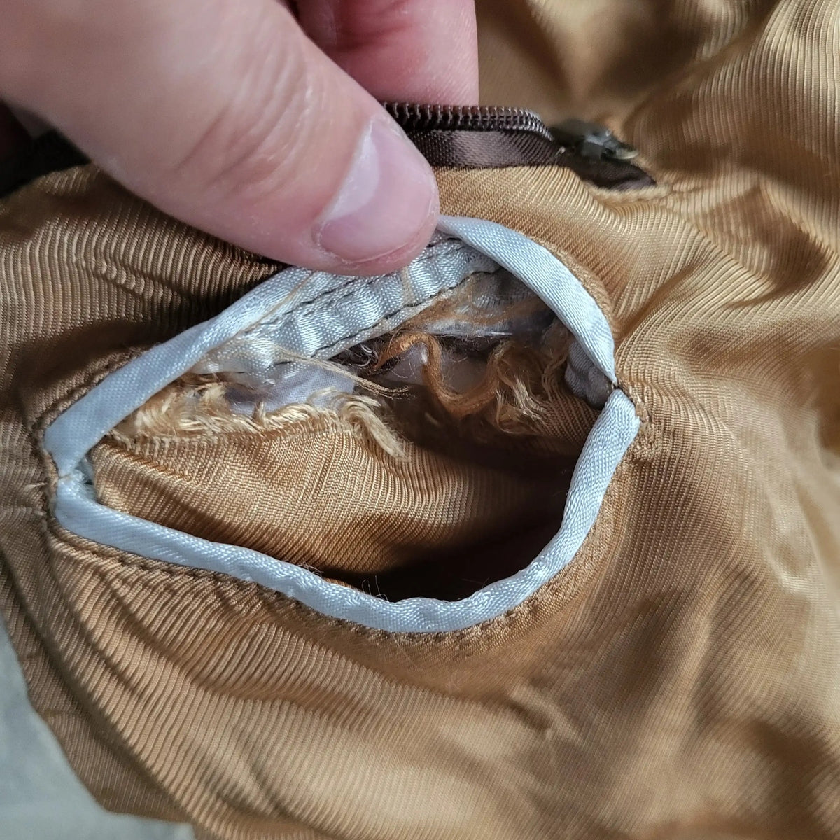 Poche de veste marron, fermeture éclair visible, marque et taille non indiquées. Fripes Sélect