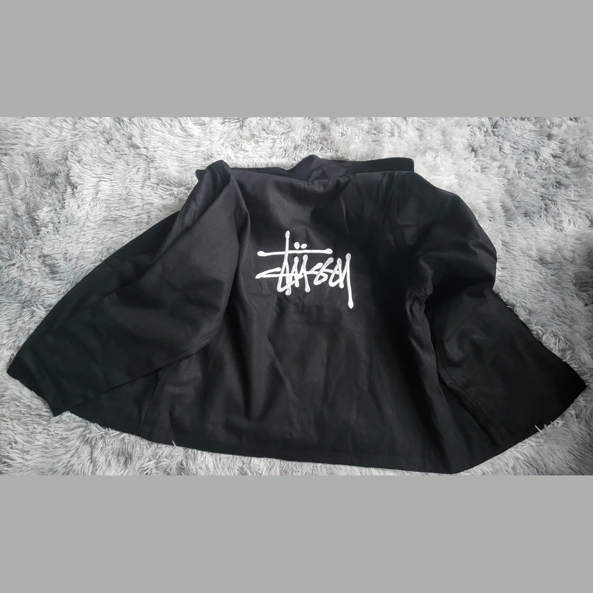 Veste noire Stüssy, logo blanc au dos, taille non indiquée. Fripes Sélect