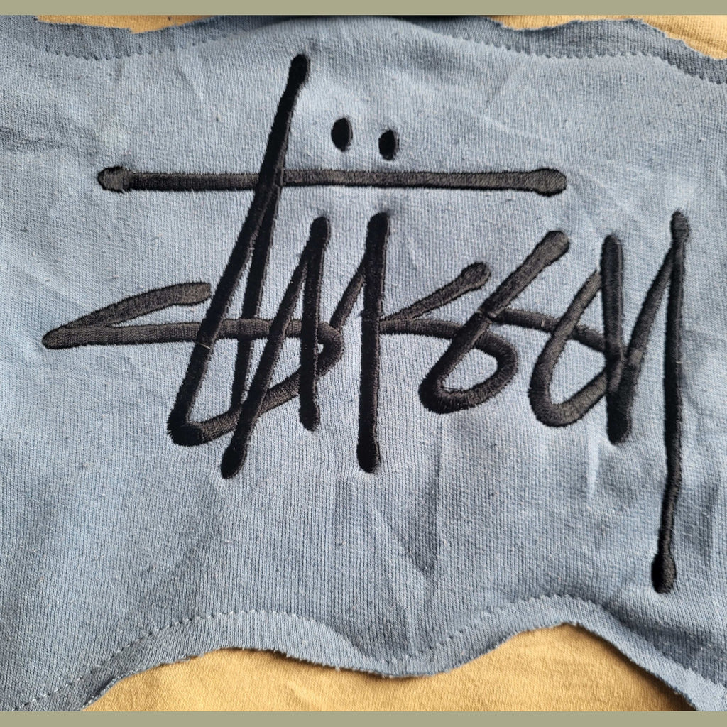Pull bleu Stüssy, logo brodé noir, taille non indiquée. Fripes Sélect