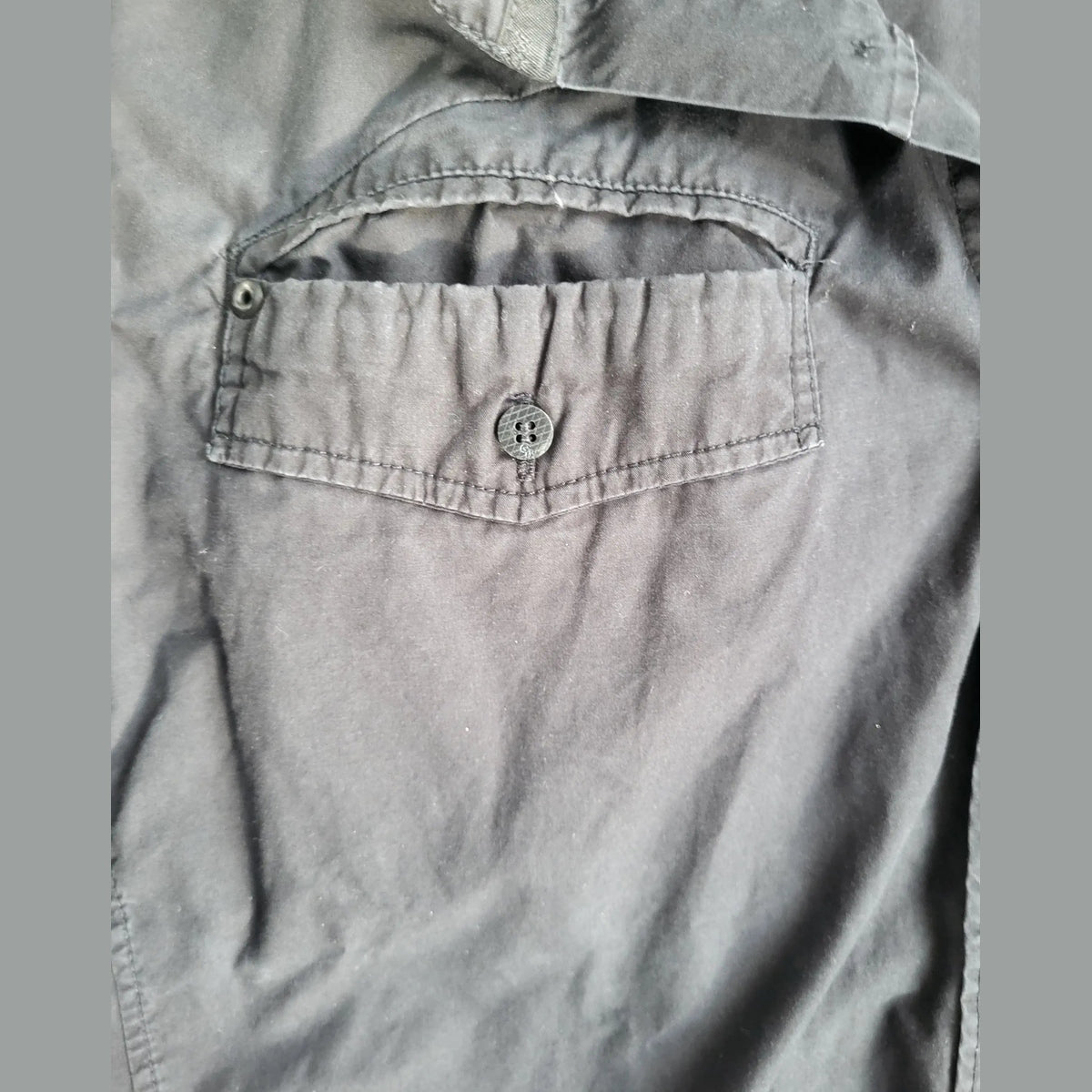 Chemise noire à poche boutonnée, marque et taille non visibles. Fripes Sélect