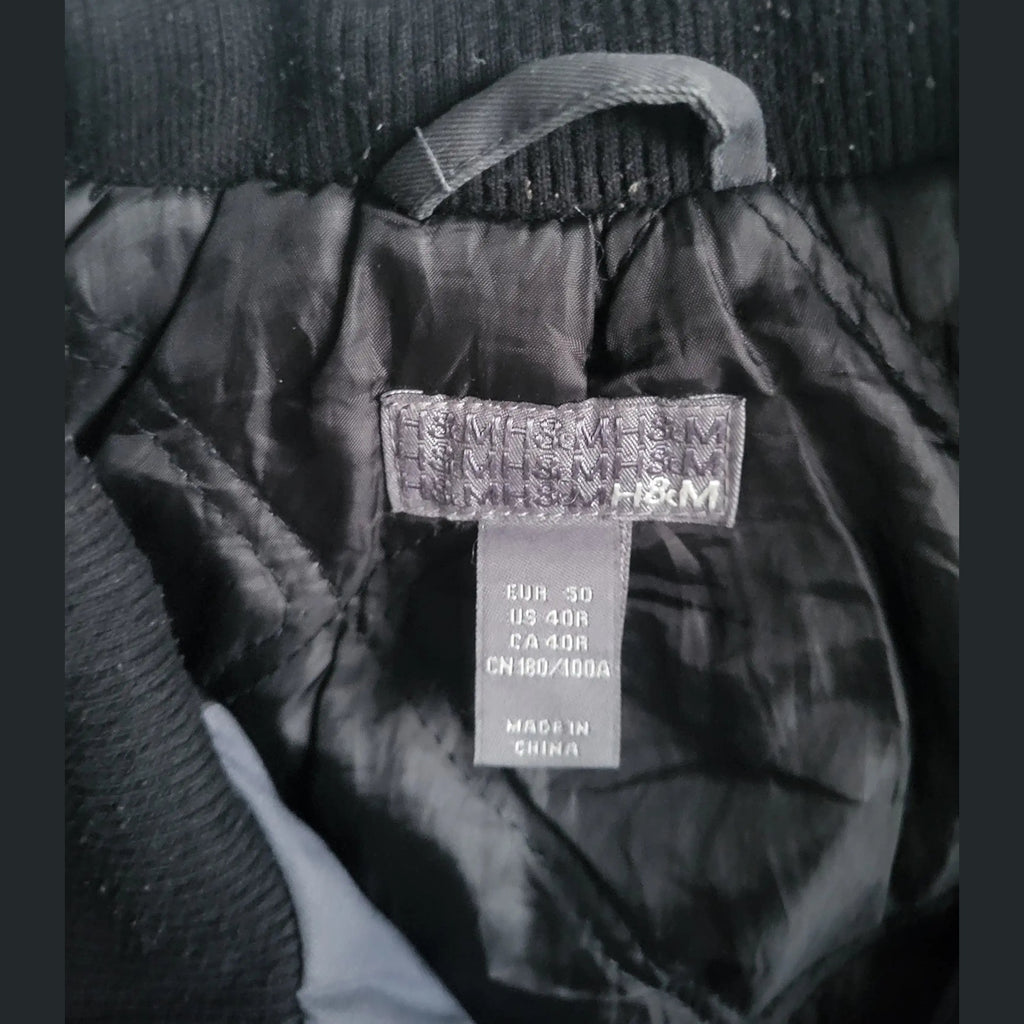 Veste noire H&M taille 50, col côtelé, étiquette intérieure visible. Fripes Sélect