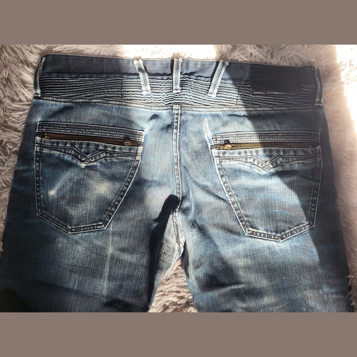 Jean bleu délavé, marque non visible, poches zippées, taille non indiquée. Fripes Sélect