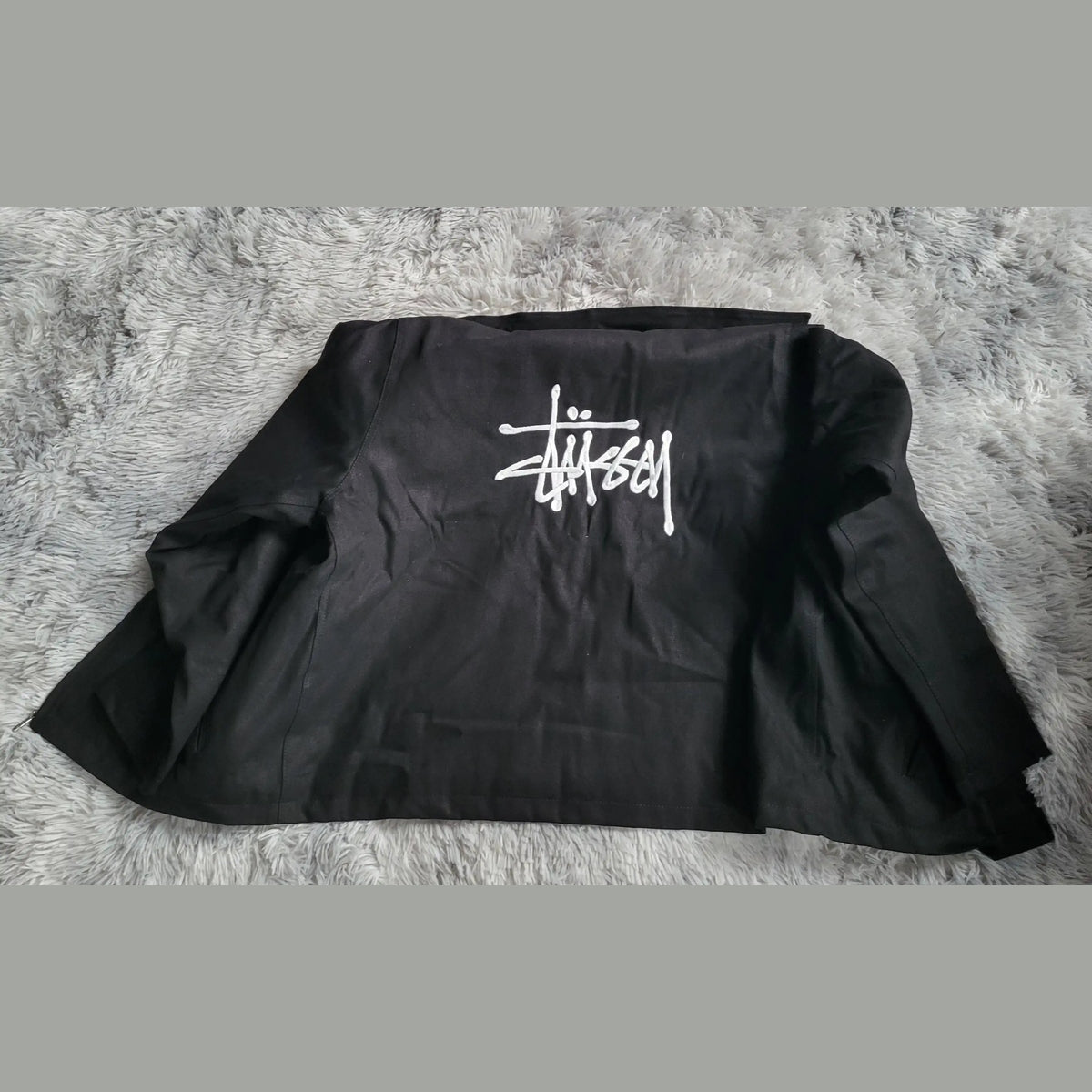 Veste noire Stüssy, logo blanc au dos, taille non visible. Fripes Sélect