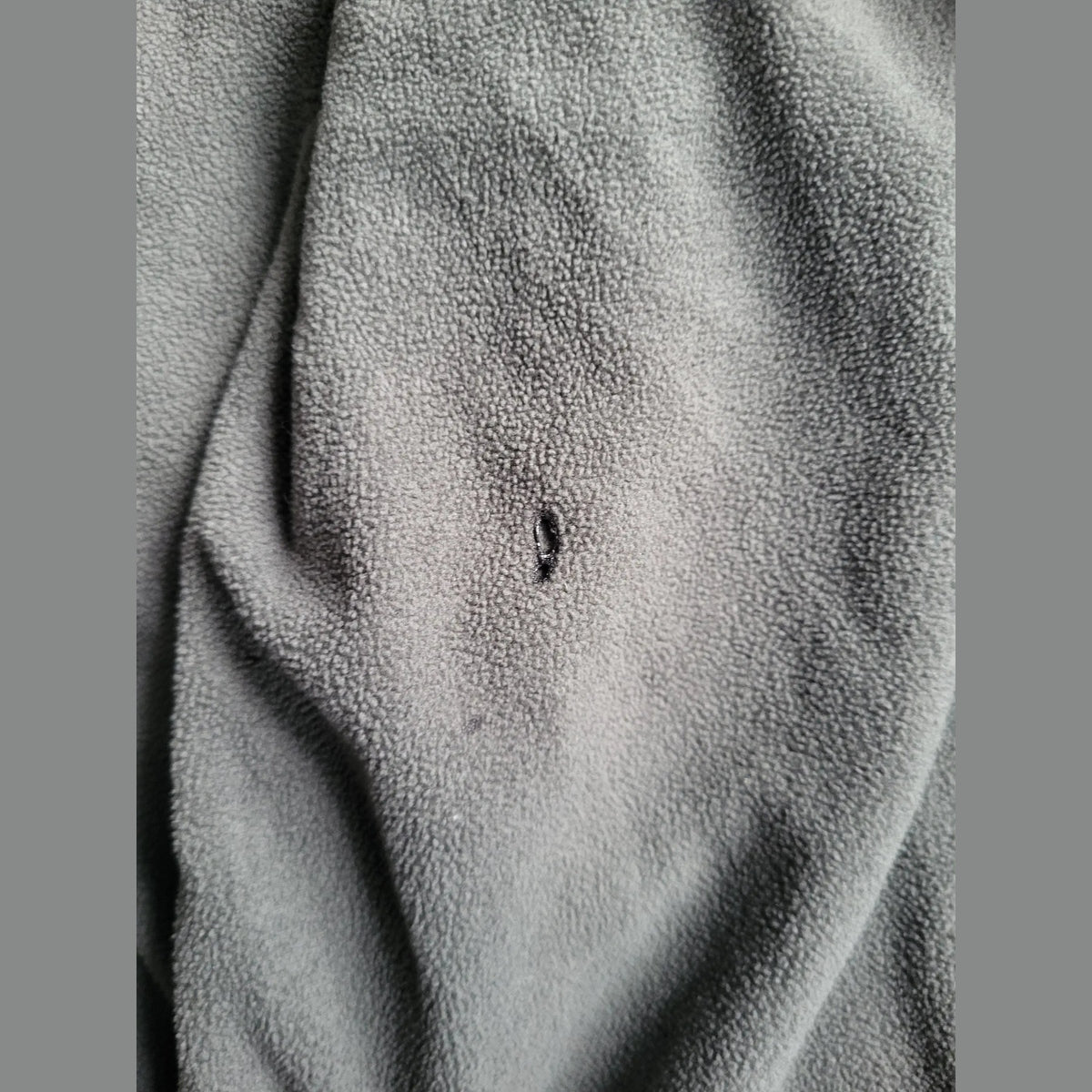 Veste polaire gris foncé, taille non visible, petite déchirure. Fripes Sélect