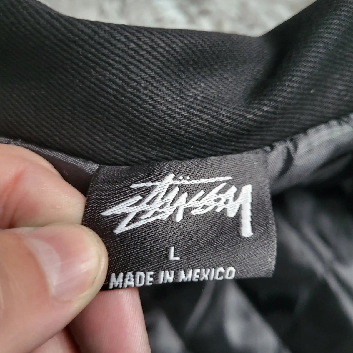 Veste noire Stüssy taille L, étiquette visible. Fripes Sélect
