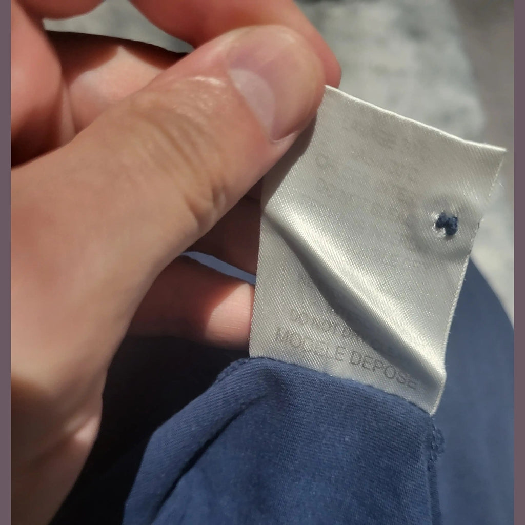 Étiquette d'un vêtement bleu, marque et taille non visibles, Fripes Sélect