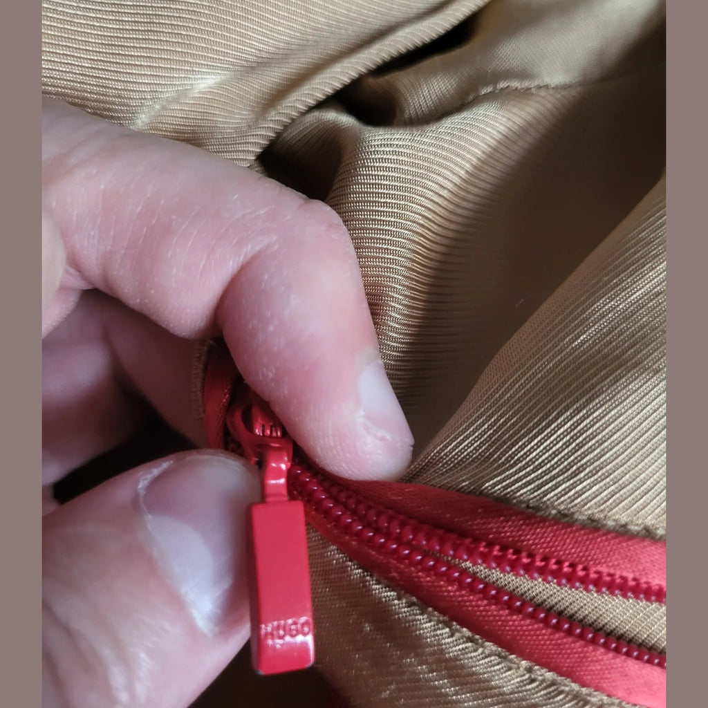 Veste beige avec fermeture éclair rouge, marque non visible, taille non indiquée. Fripes Sélect