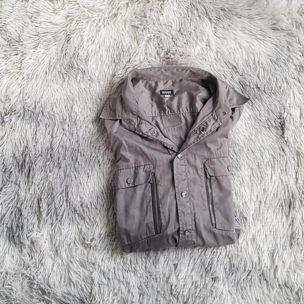 Veste grise Versace, taille M, posée sur tapis en fourrure. Fripes Sélect