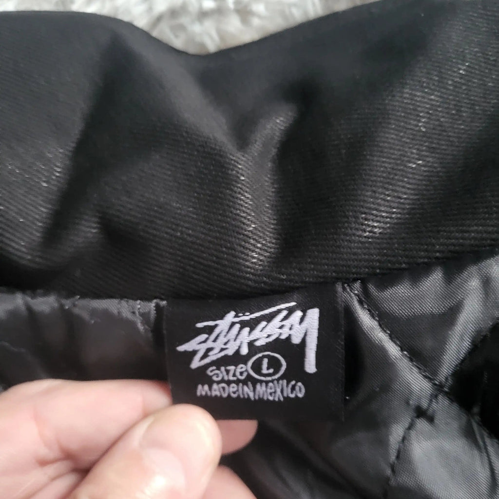 Veste noire Stüssy taille L, étiquette visible. Fripes Sélect