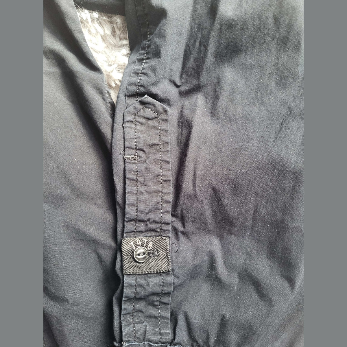 Veste noire, doublure en fausse fourrure, bouton marqué 1998, taille non visible. Fripes Sélect