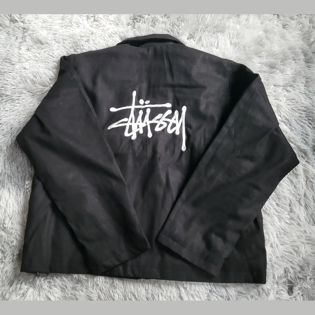 Veste noire Stüssy, logo blanc au dos, taille non visible. Fripes Sélect