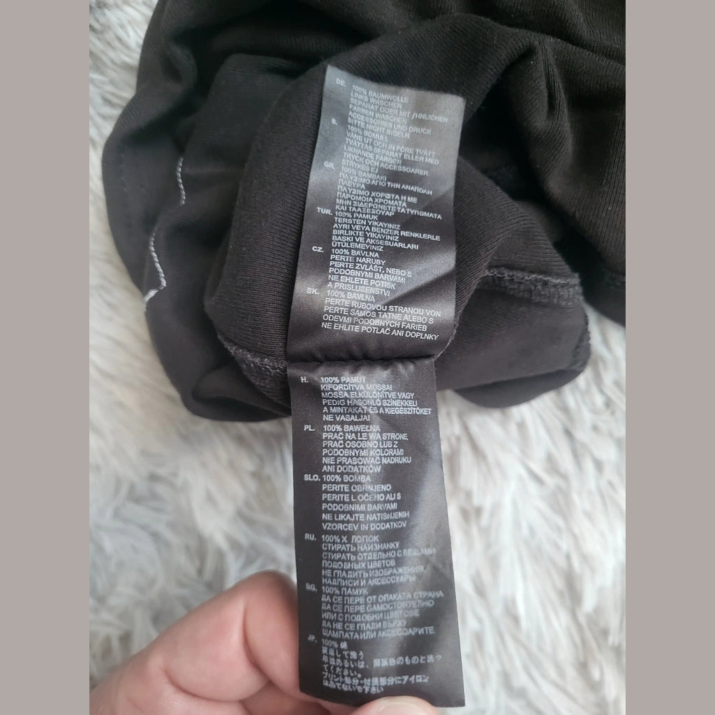 Étiquette d’un t-shirt noir, 100% coton, taille S visible, Fripes Sélect