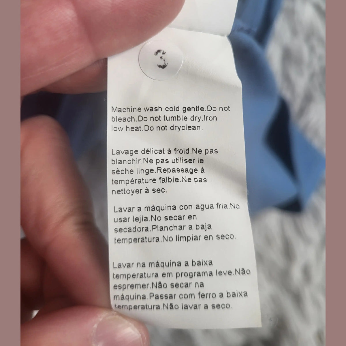 Étiquette d’un vêtement bleu taille S, instructions d’entretien visibles. Fripes Sélect