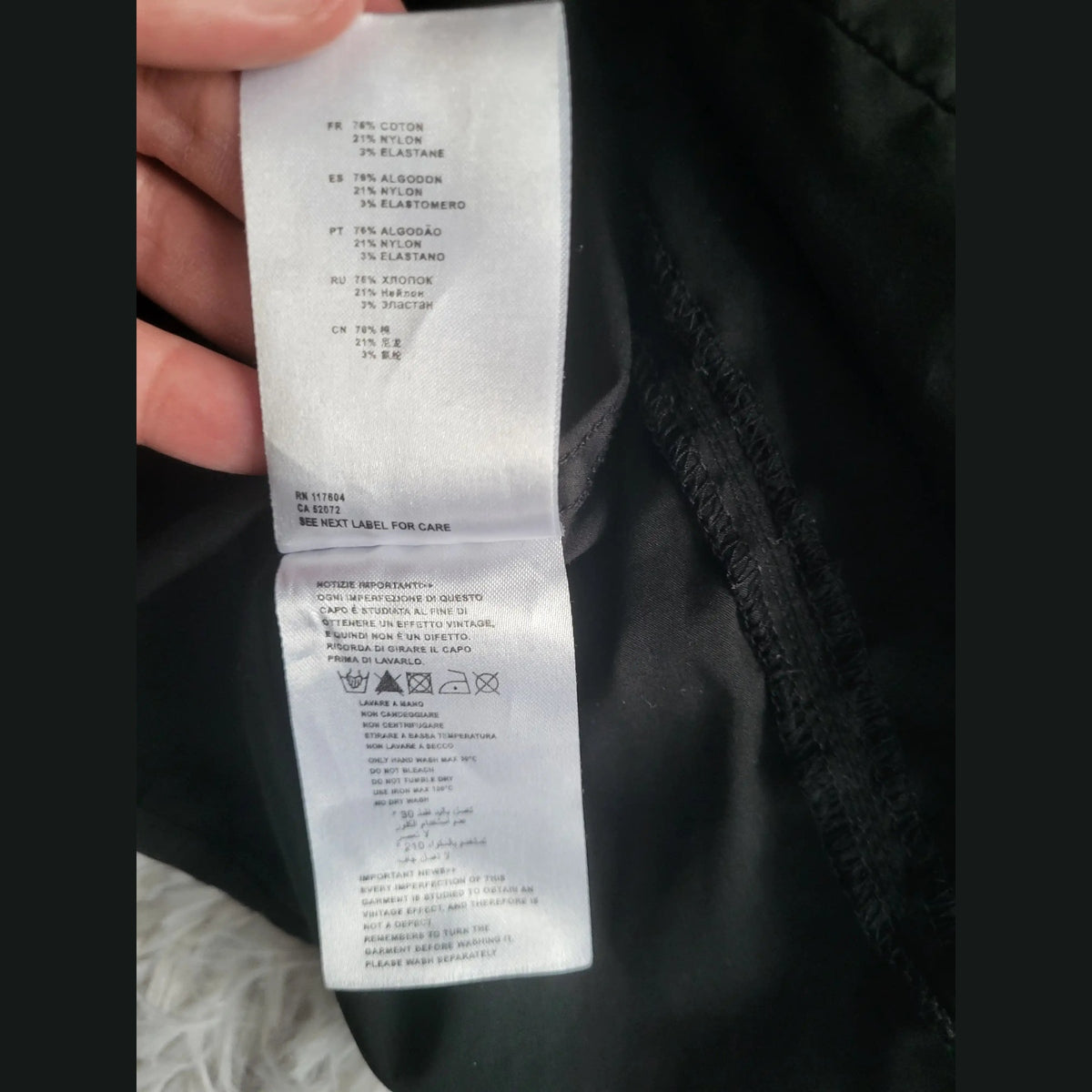 Étiquette d’un vêtement noir, taille et marque non visibles, composition coton, nylon, élasthanne. Fripes Sélect