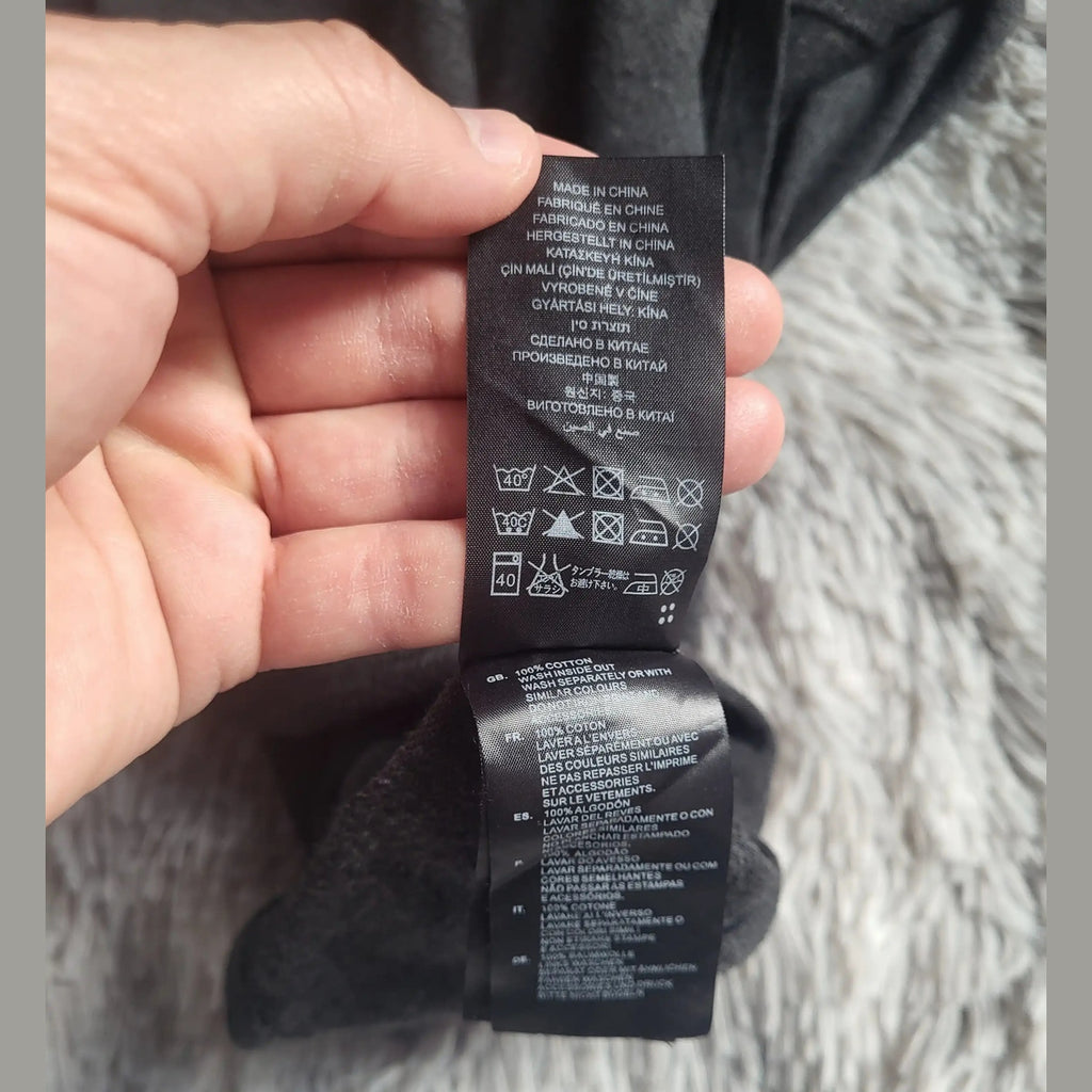 Étiquette vêtement noir, 100% coton, aucune marque ou taille visible. Fripes Sélect