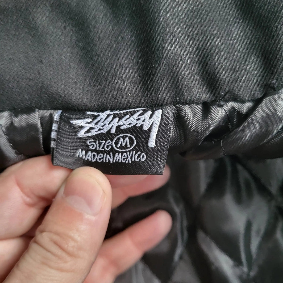 Veste Stüssy noire taille M, étiquette visible. Fripes Sélect