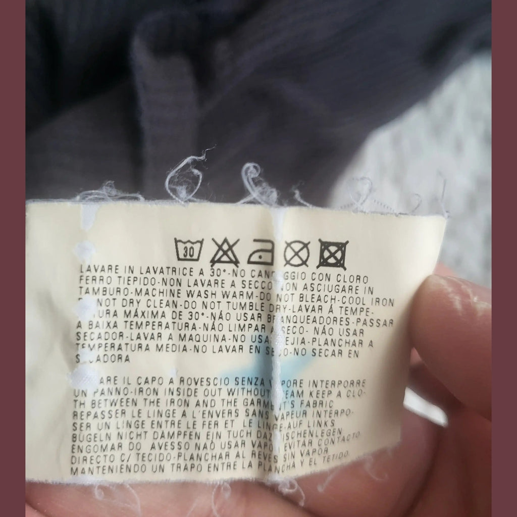 Étiquette d'entretien d'un vêtement noir, taille non visible, marque non visible, Fripes Sélect