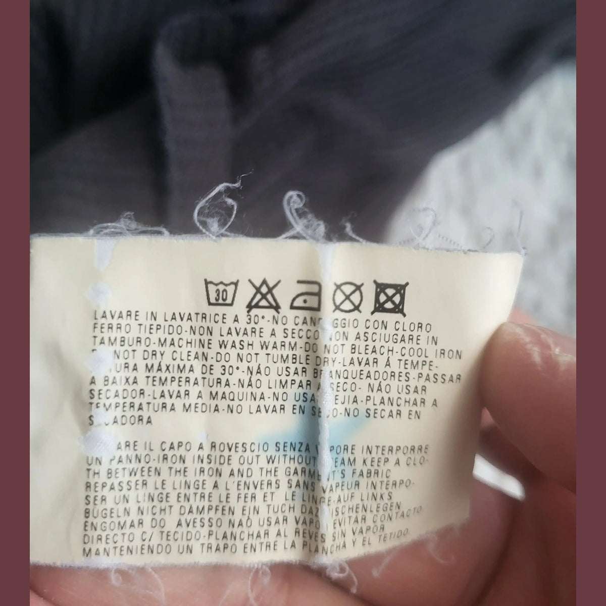 Étiquette d'entretien d'un vêtement noir, taille non visible, marque non visible, Fripes Sélect