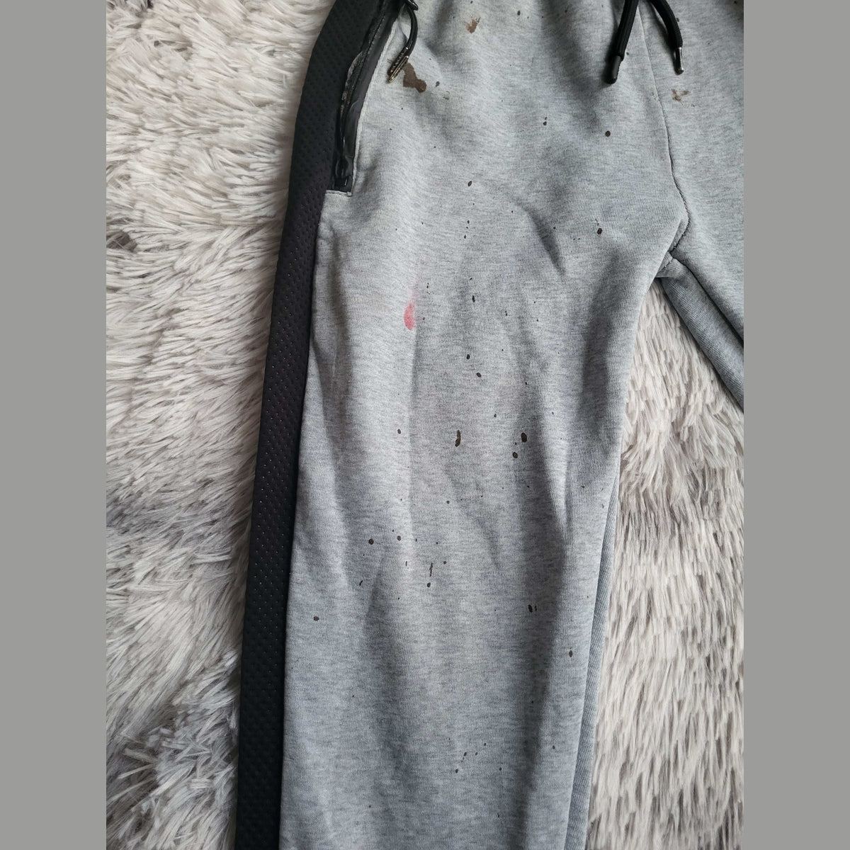 Pantalon de jogging gris à bandes noires, taches visibles, taille non indiquée. Fripes Sélect