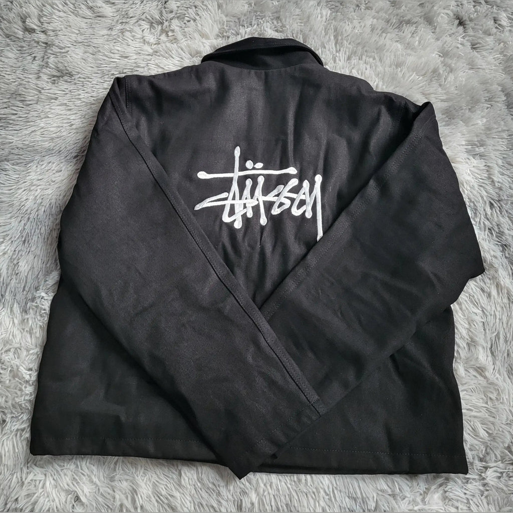 Veste noire Stüssy, logo blanc au dos, taille non indiquée. Fripes Sélect