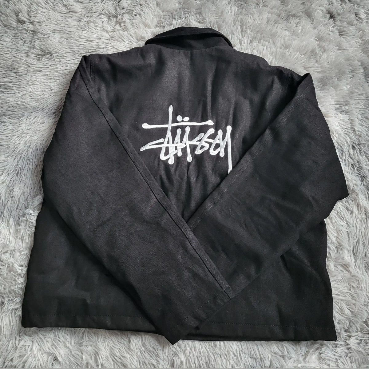 Veste noire Stüssy, logo blanc au dos, taille non indiquée. Fripes Sélect