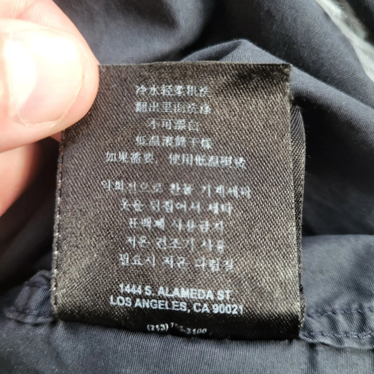 Étiquette intérieure sur vêtement noir, taille et marque non visibles, Fripes Sélect