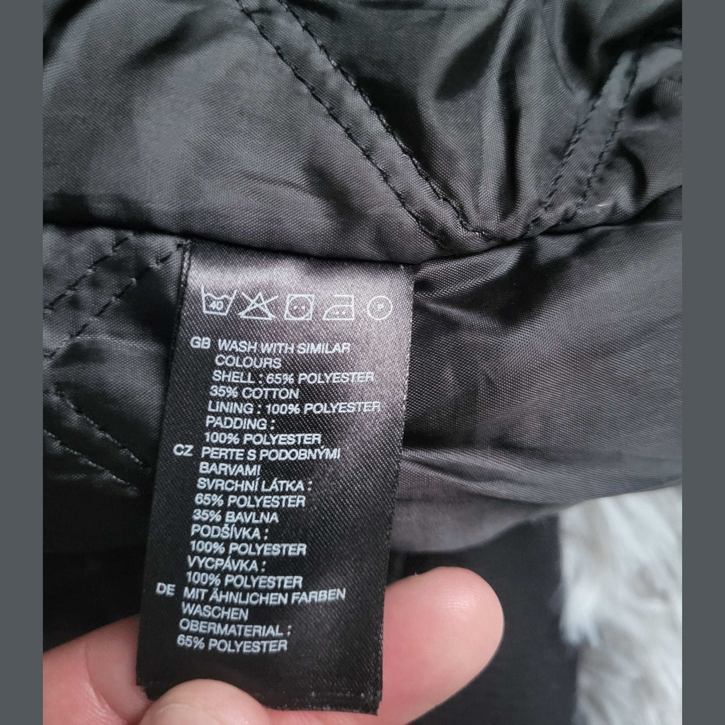 Veste noire, étiquette matière visible, marque non indiquée, taille non précisée. Fripes Sélect