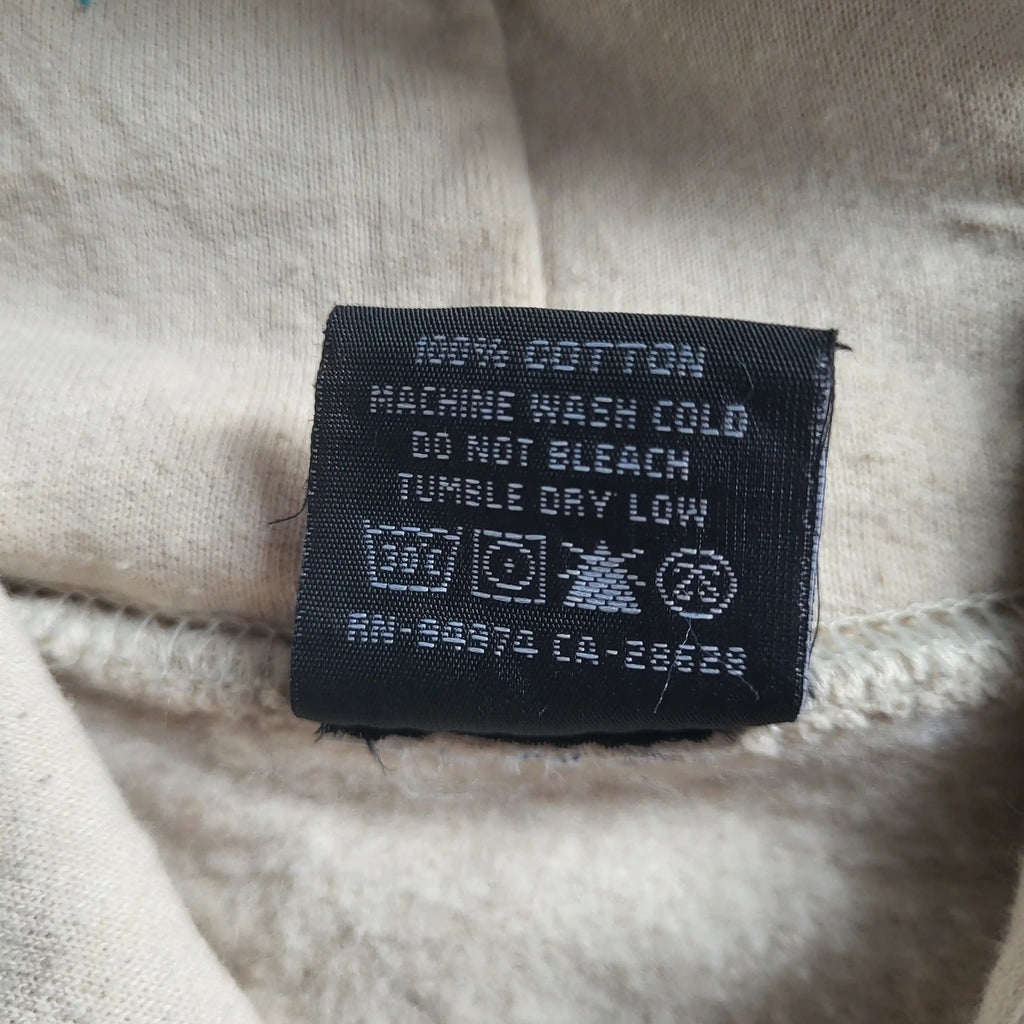 Étiquette d'entretien sur un vêtement beige 100% coton, taille non visible, Fripes Sélect